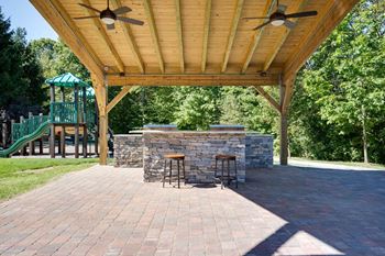 A patio with a bar and two stools under a roof.